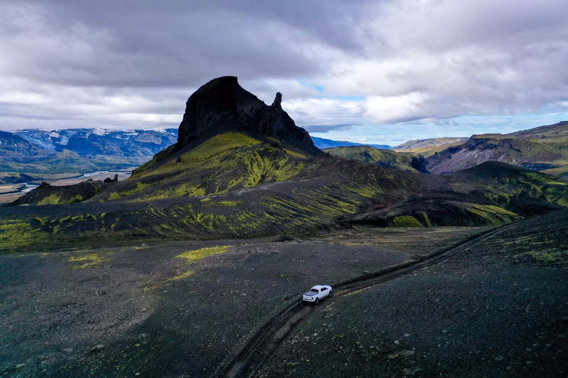 White super jeep on volcanic highland trail toward dramatic black peak in Fjallabak Nature Reserve, Iceland