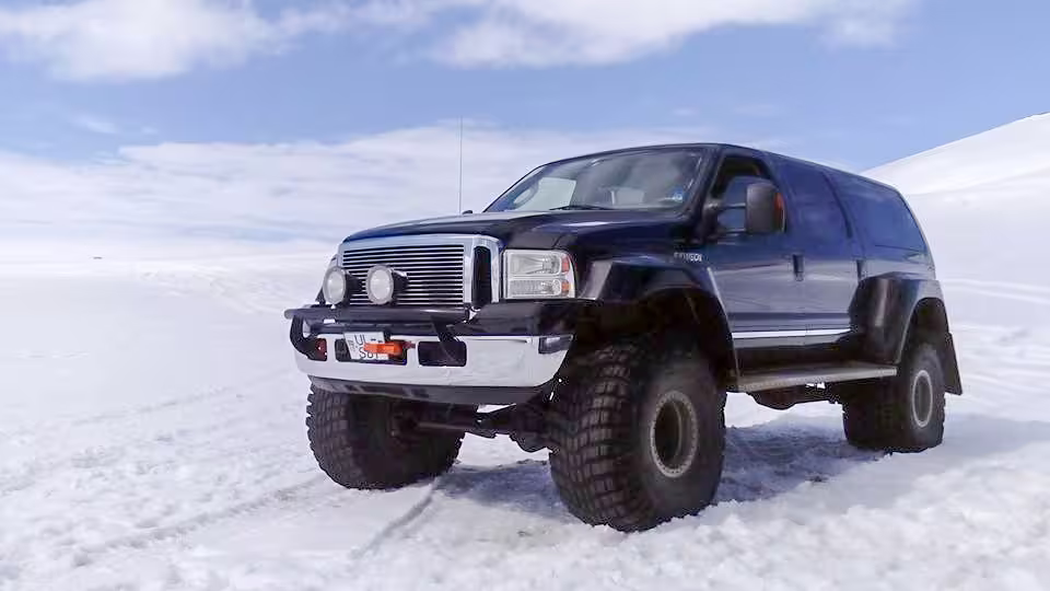 Black lifted super jeep with oversized tires driving on Iceland's snow-covered landscape