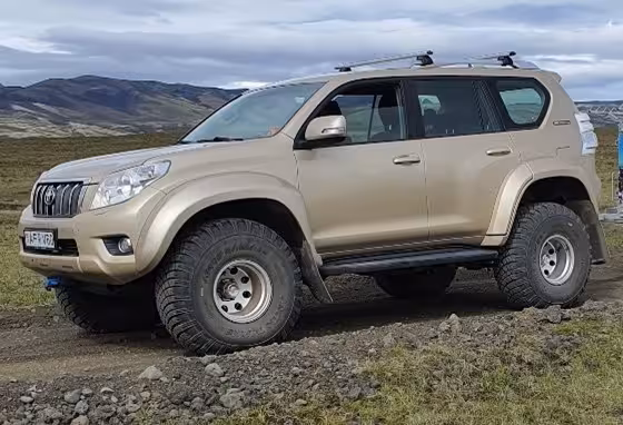 Gold Toyota Land Cruiser super jeep with oversized off-road tires on rocky terrain in Iceland
