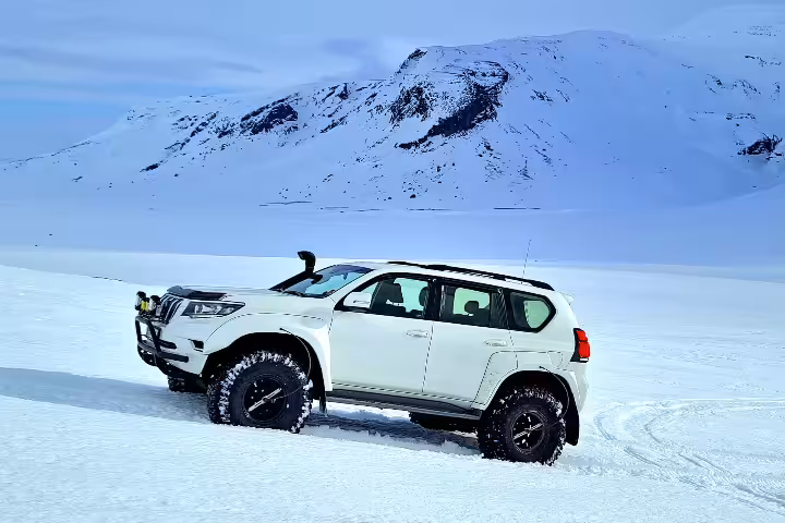 White lifted Toyota Land Cruiser super jeep on Langjokull glacier snowfield with snowy mountains in Iceland