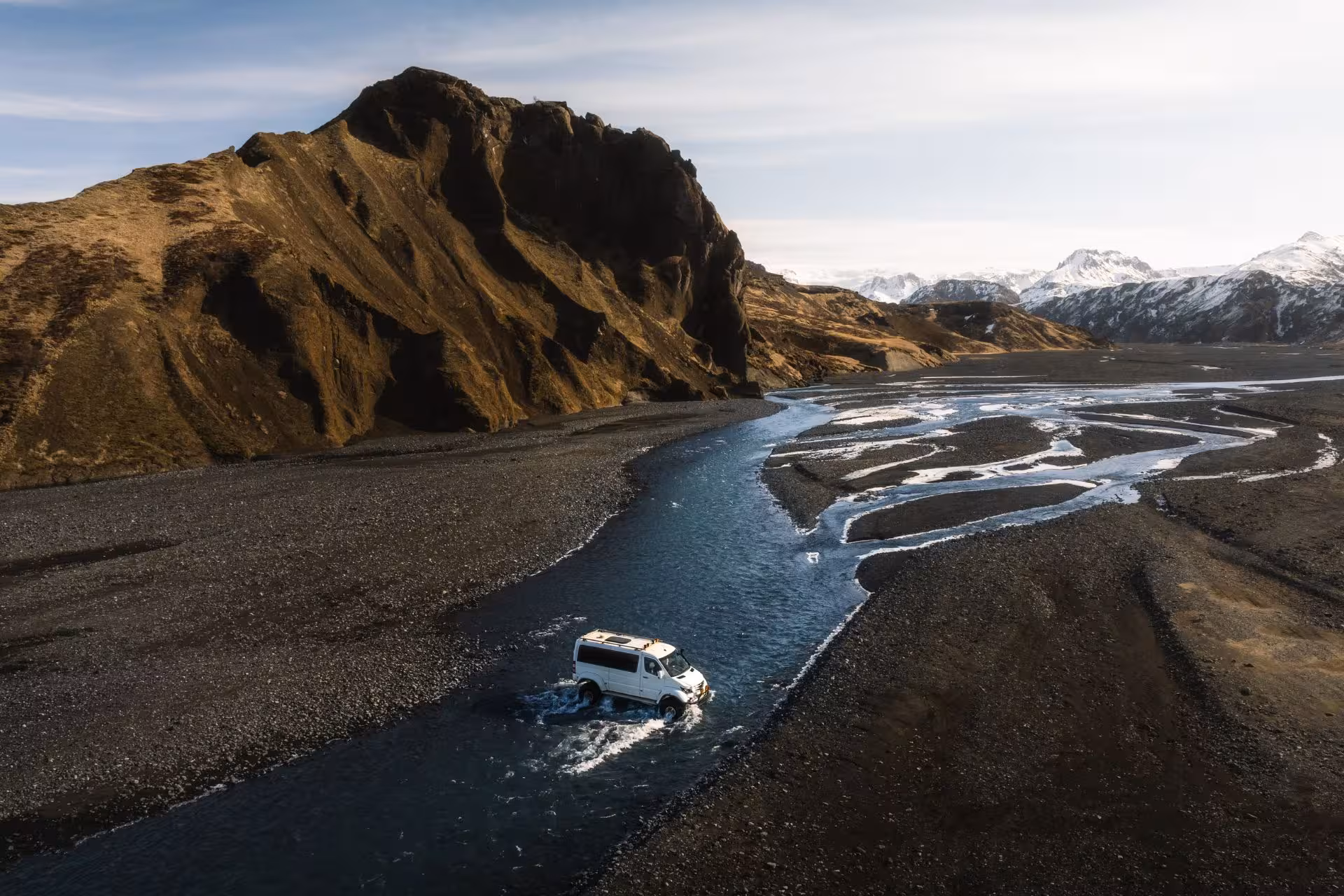 White super jeep crossing a glacial river in Thorsmork Nature Reserve with volcanic mountains behind