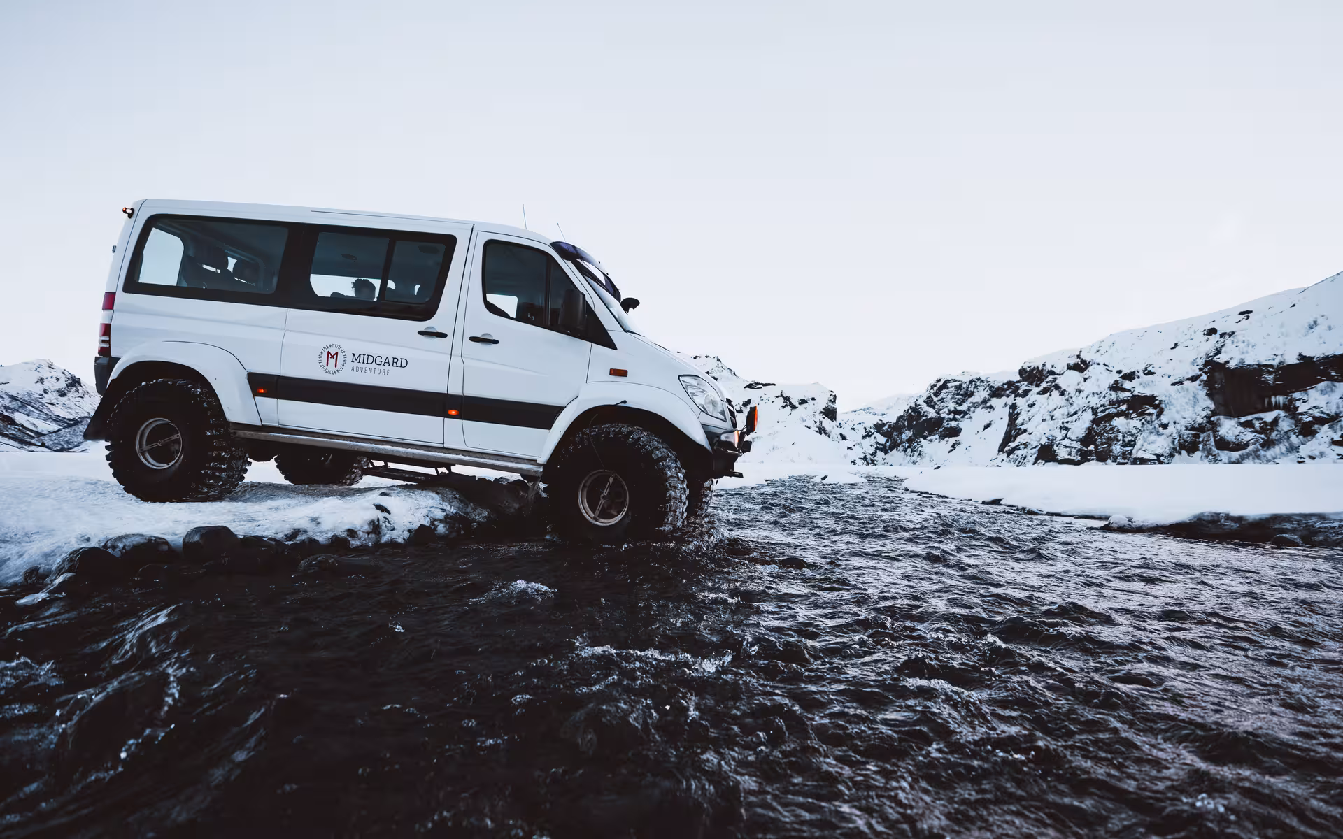 Midgard Adventure super jeep crossing a glacial river in snowy Thorsmork Iceland