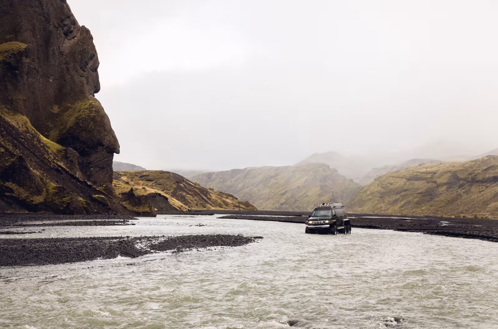 4x4 super jeep crossing glacial river in Thorsmork Iceland with mossy canyon walls