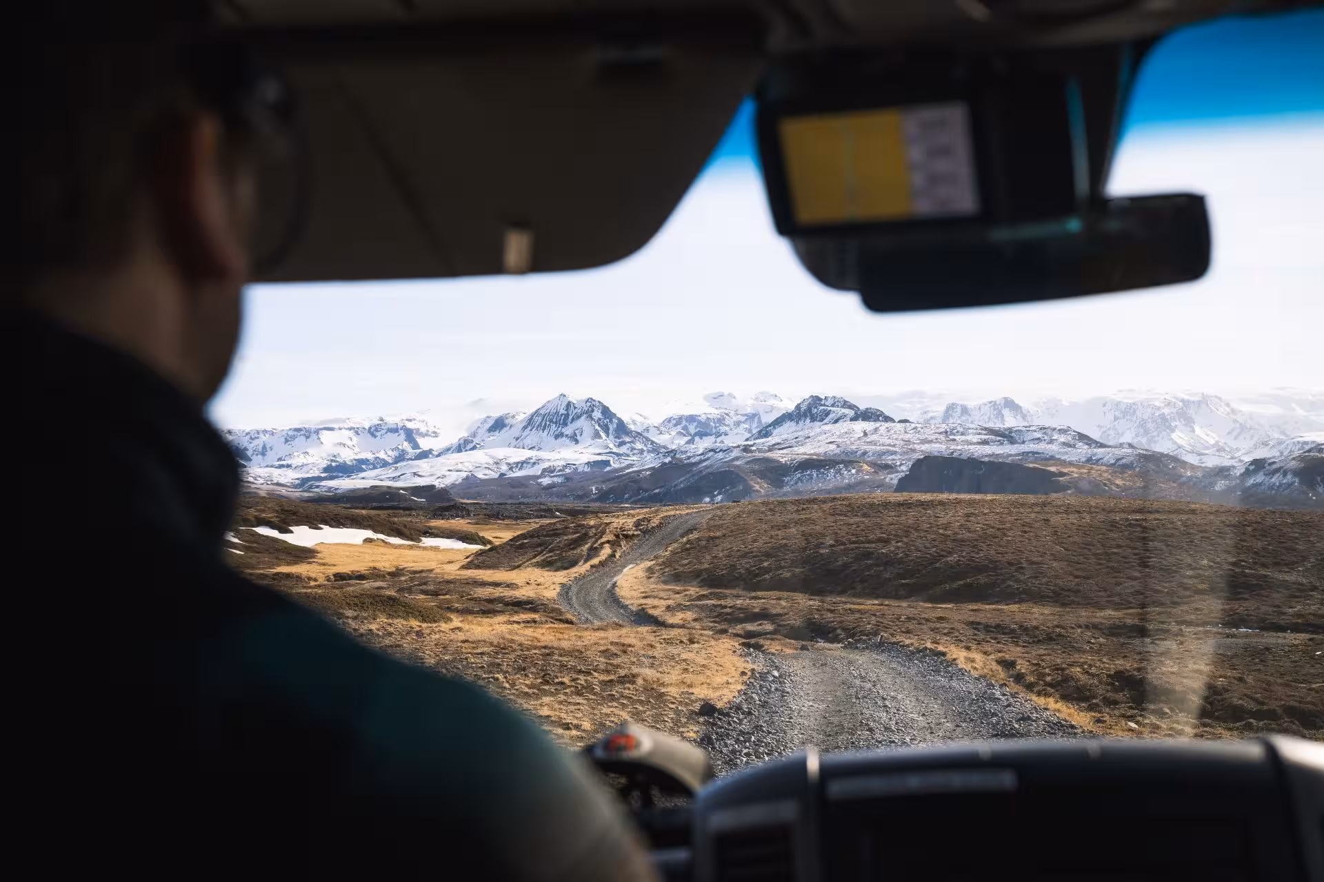 Driver navigating a gravel road toward snow-capped mountains in Thorsmork in a Super Jeep