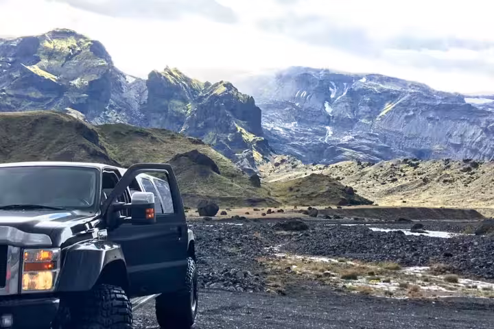 Black super jeep parked on volcanic terrain with dramatic Thorsmork mountain highlands in background
