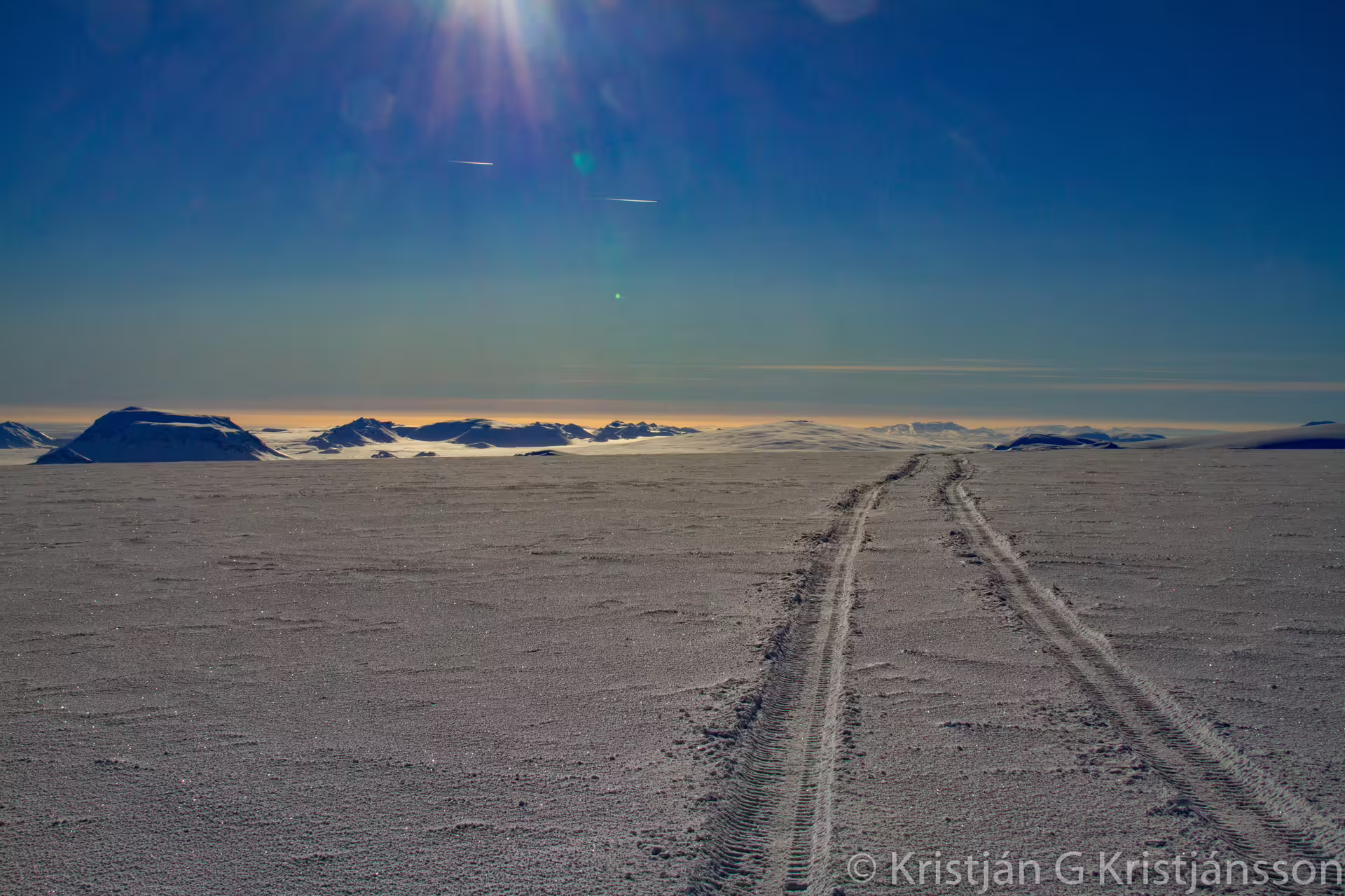 Super jeep tire tracks crossing vast glacier landscape with snow-capped mountains in Iceland