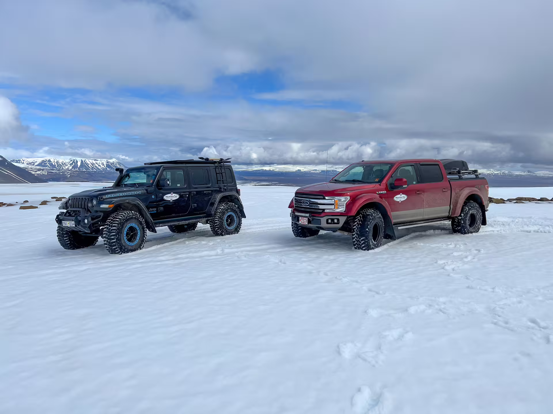 Black Jeep Wrangler Rubicon and red Ford F-150 super jeeps parked on a glacier in Iceland