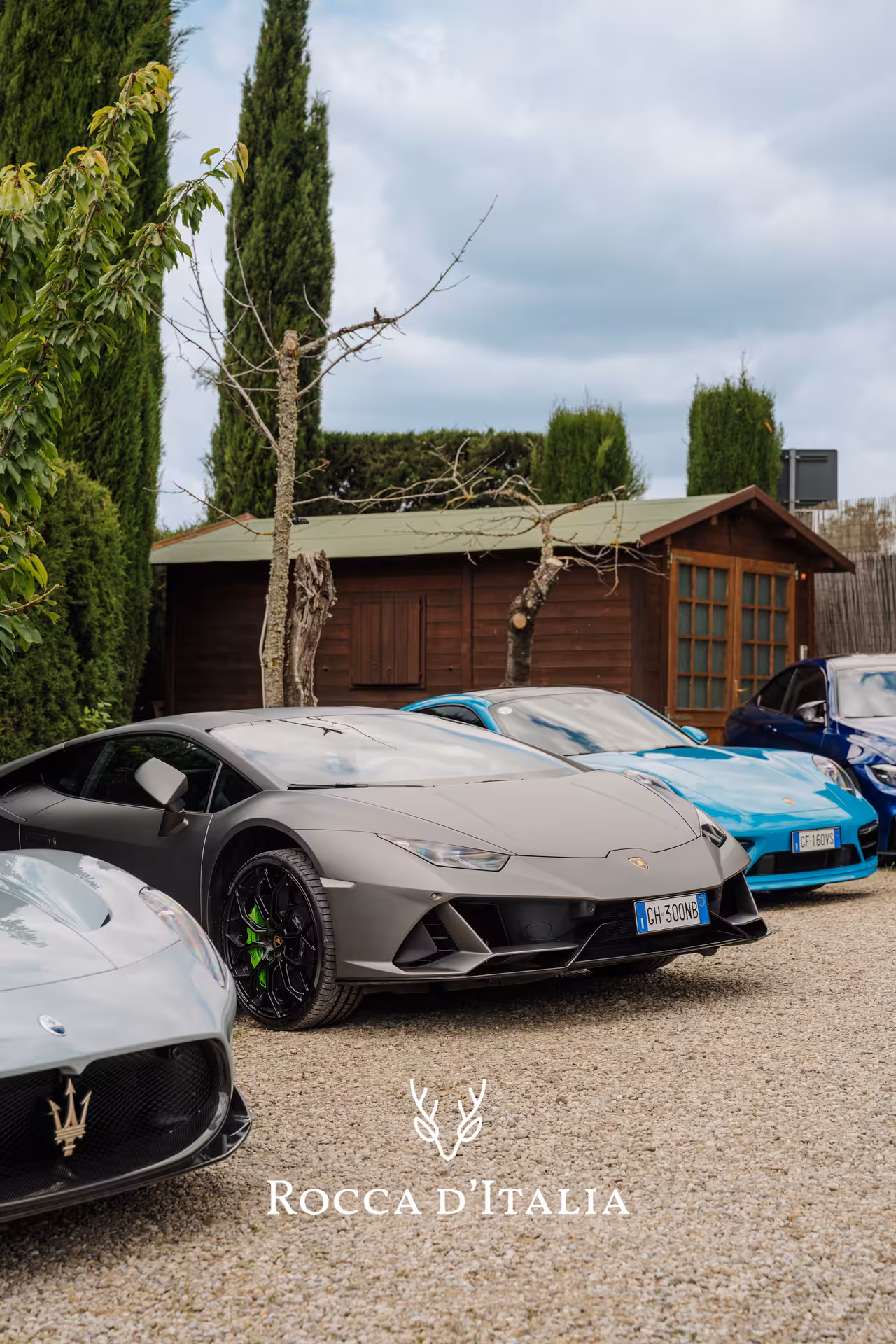 Lamborghini Huracán and Porsche supercars lined up on gravel in Tuscan countryside