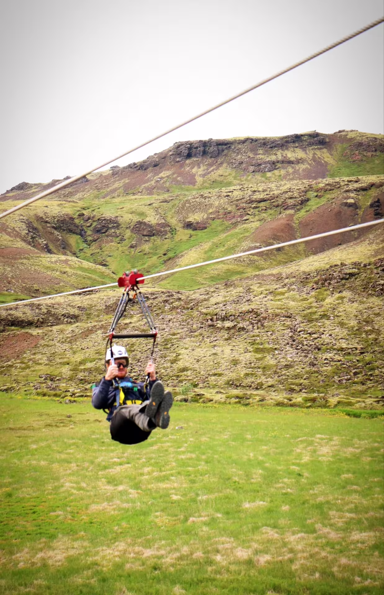 Person enjoying an exhilarating zipline ride over lush green hills on the thrilling Superman Ride (Fast as a Falcon) tour.