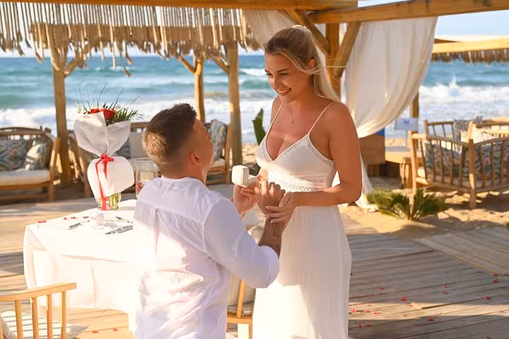 Romantic beachside proposal in Hersonissos with a couple embracing under a wooden pergola, surrounded by sea views.