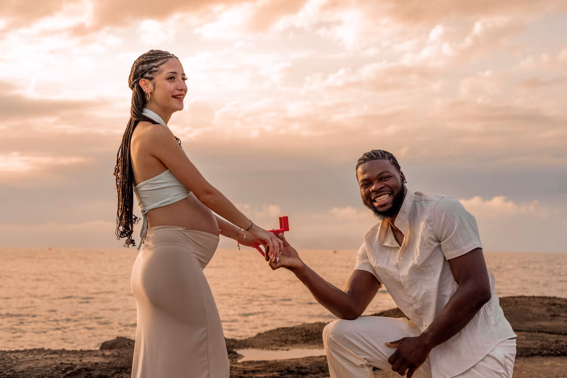 Man proposes to pregnant woman by the sea at Heraklion Venetian Port, capturing a joyful surprise engagement moment.