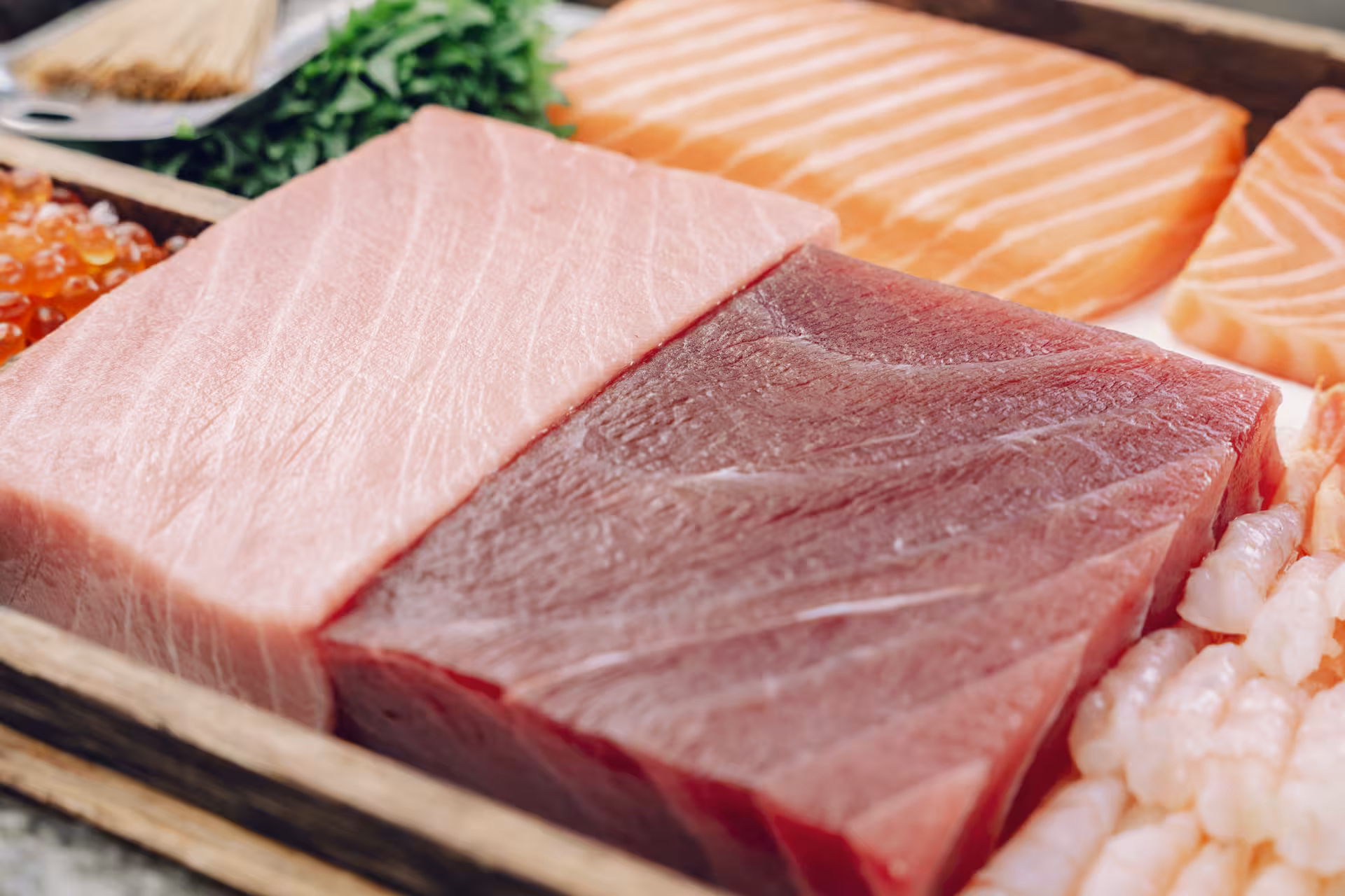 Fresh sashimi ingredients for sushi masterclass, featuring tuna and salmon cuts with shrimp and roe on tray