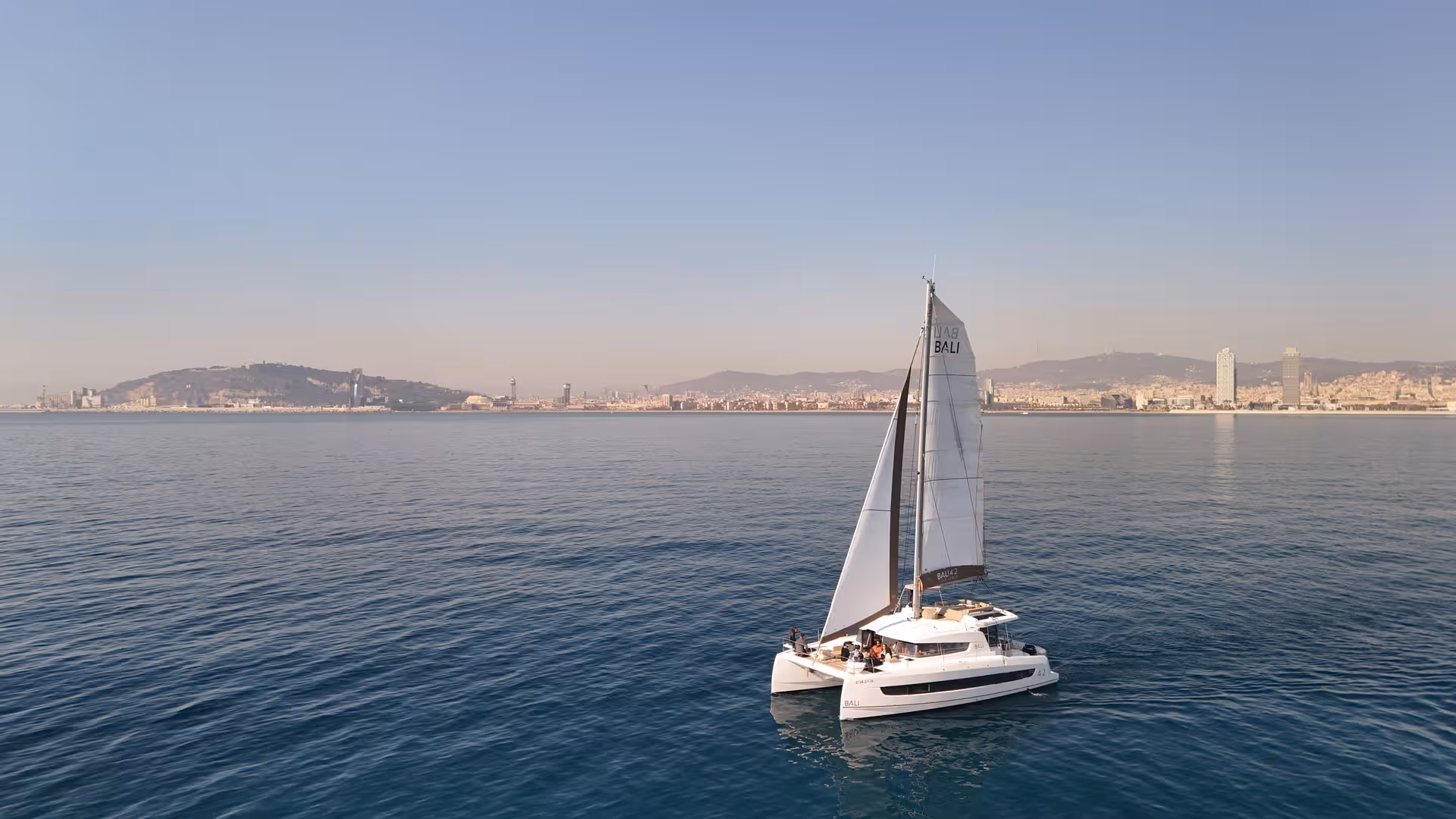 Sailboat cruising on calm sea near a city skyline, unrelated image for sushi masterclass product listing