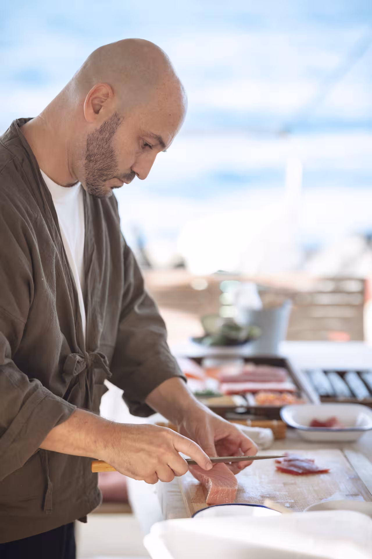 Chef demonstrating sashimi slicing techniques during hands-on Sushi Masterclass with fresh tuna at prep station