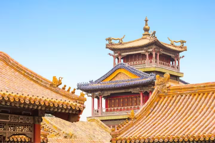 Intricate Chinese temple rooftops with ornate details under a clear blue sky, highlighting Suzhou's historical architecture.