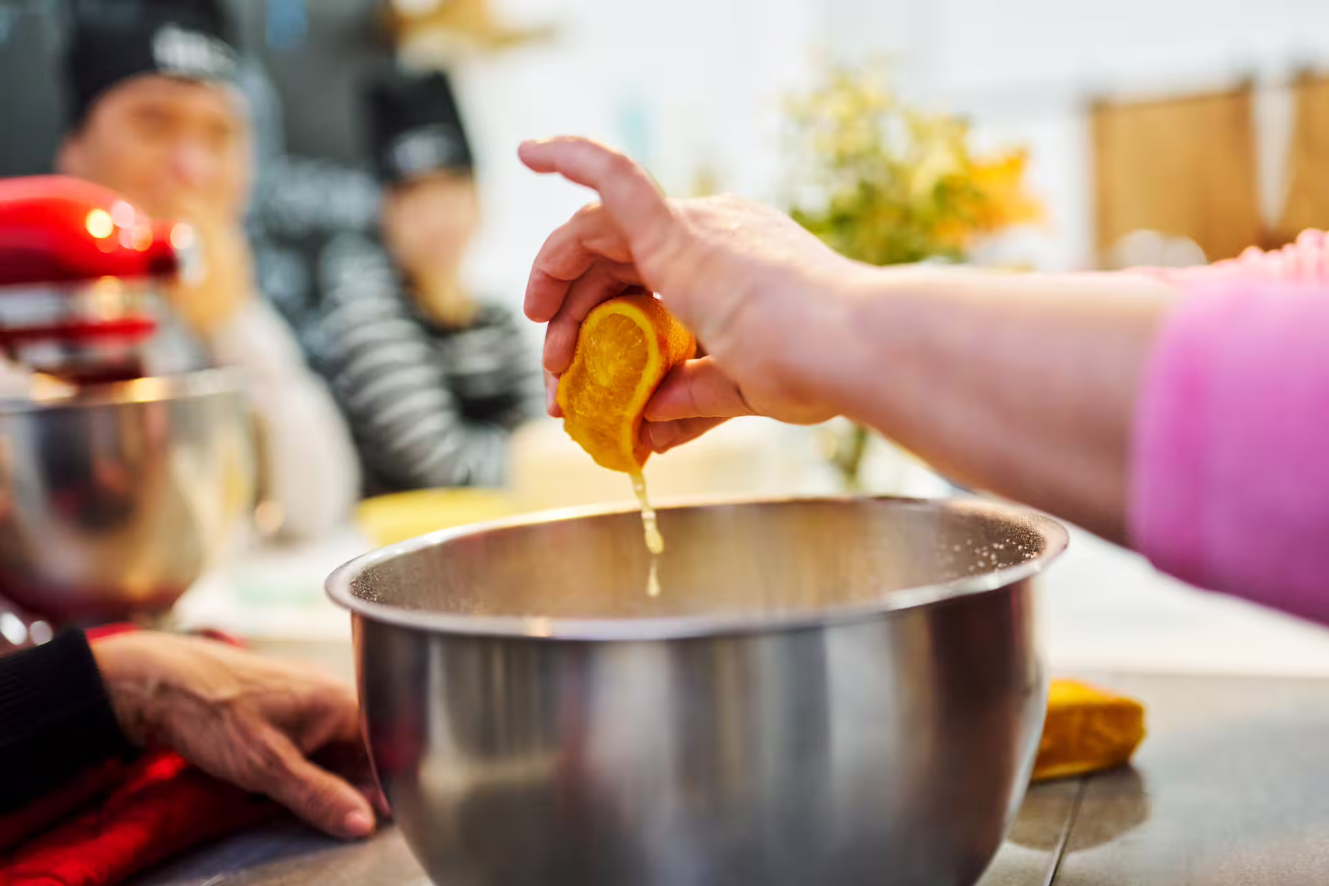 A participant squeezes fresh orange juice into a mixing bowl at the interactive Sweet Escape: Bake & Take Workshop.