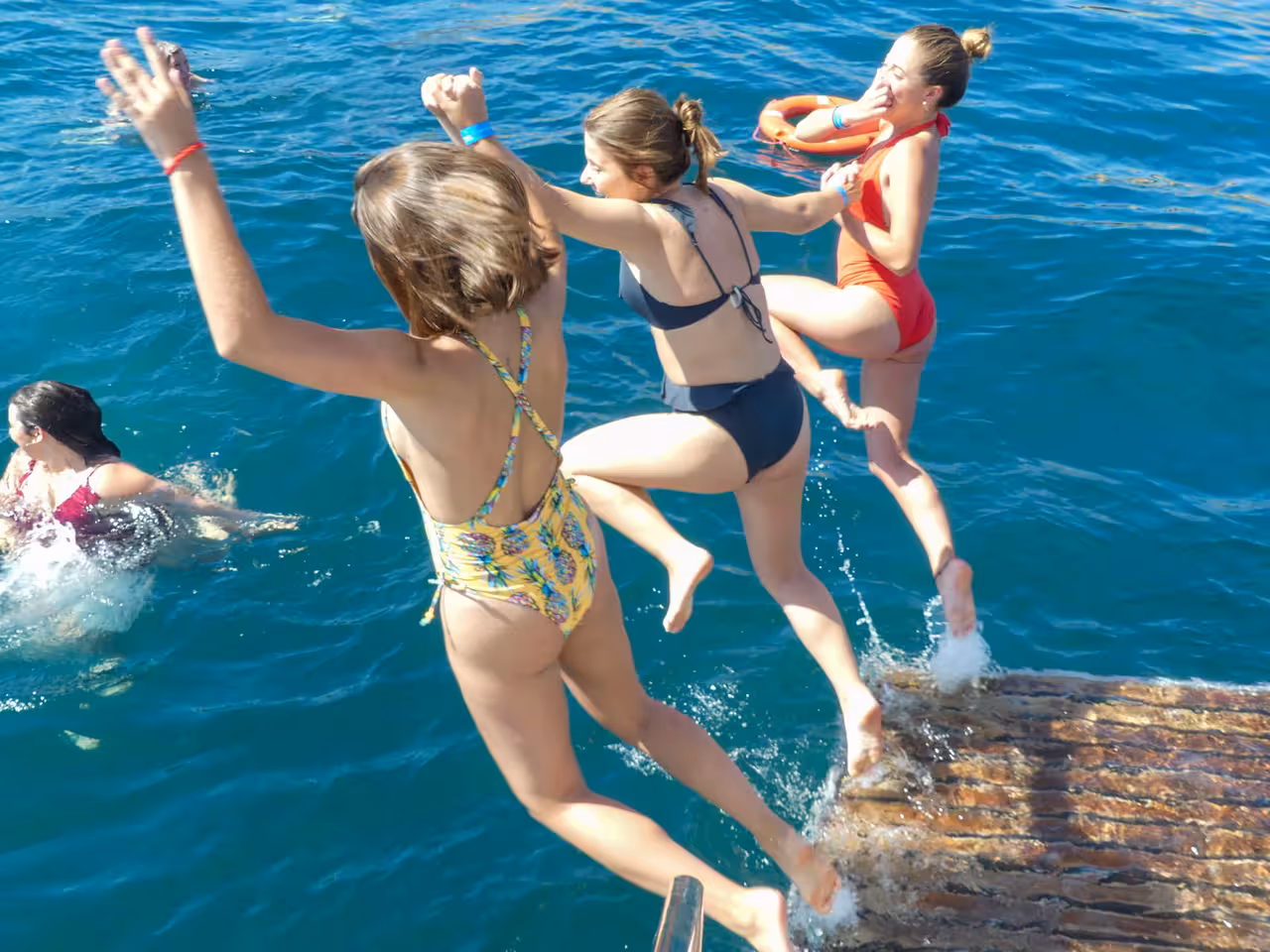 Excited guests leaping into crystal-clear blue waters during a fun Albufeira Benagil Caves coastline boat tour swim stop