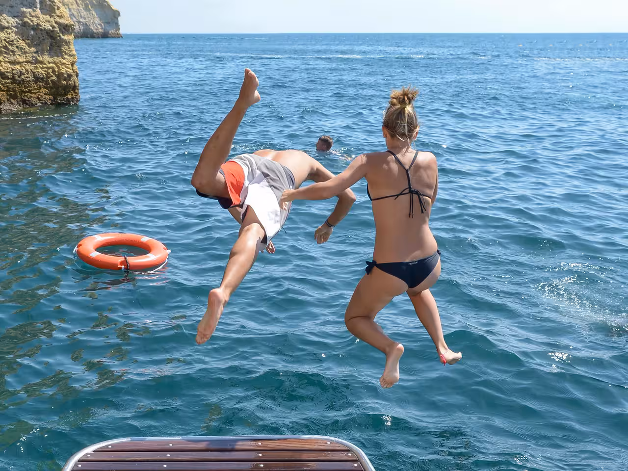 Tourists jumping off a boat into the turquoise Atlantic Ocean near Benagil Caves coastline Albufeira Portugal