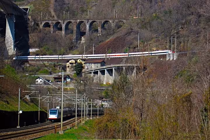 Train traversing a stunning viaduct amidst the rugged alpine terrain, highlighting the engineering marvel in Switzerland.