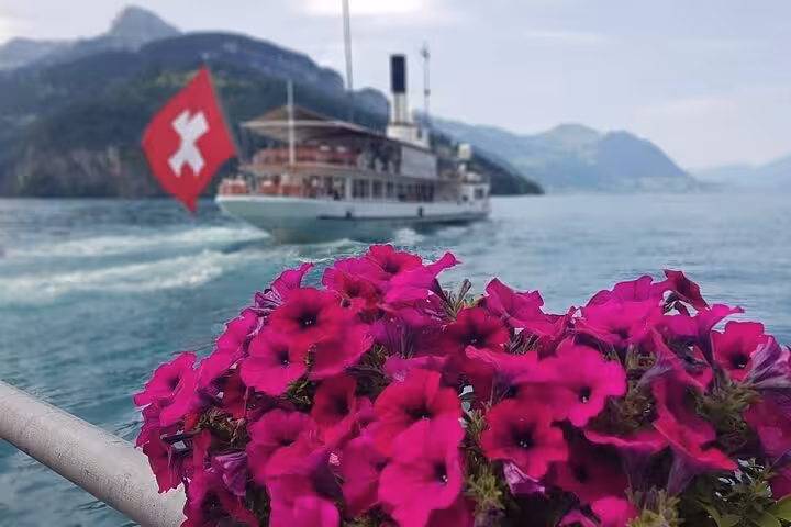 Scenic Lake Lucerne cruise with Swiss flag and vibrant flowers, highlighting Swiss tour beauty.