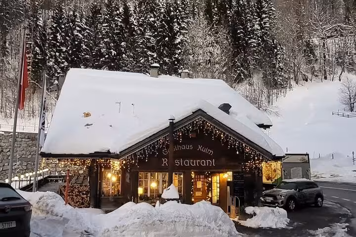Cozy snow-covered Swiss Alps restaurant with festive lights nestled in a winter wonderland setting.
