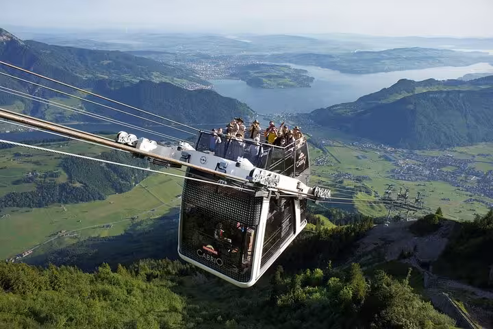 Tourists enjoying breathtaking views from a Swiss cable car over lush valleys, perfect for a custom Swiss train journey.