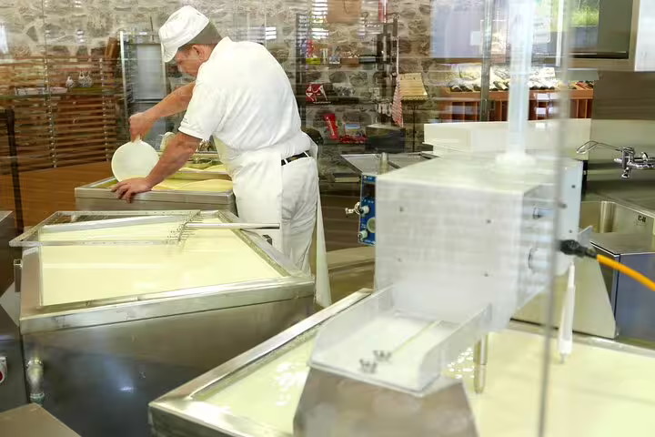 Cheesemaker crafting traditional Swiss cheese in Engelberg on Lucerne tour with cheese and Mt. Titlis highlights.