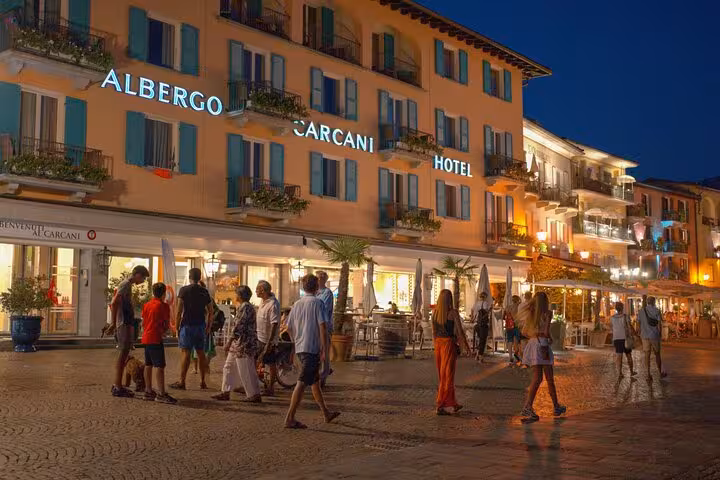 Evening view of Albergo Carcani Hotel with people enjoying the vibrant atmosphere in a Swiss town square.