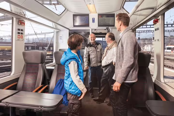 Passengers enjoy a comfortable ride inside a modern Swiss train, highlighting the social atmosphere of the journey.