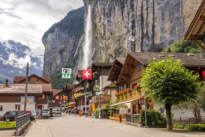 Picturesque Swiss village street with waterfall view, part of the exclusive panoramic train journey in Switzerland.