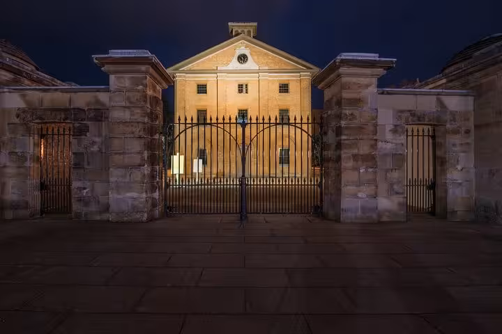 Historic sandstone building with iron gates illuminated at night, Sydney ghost tour location