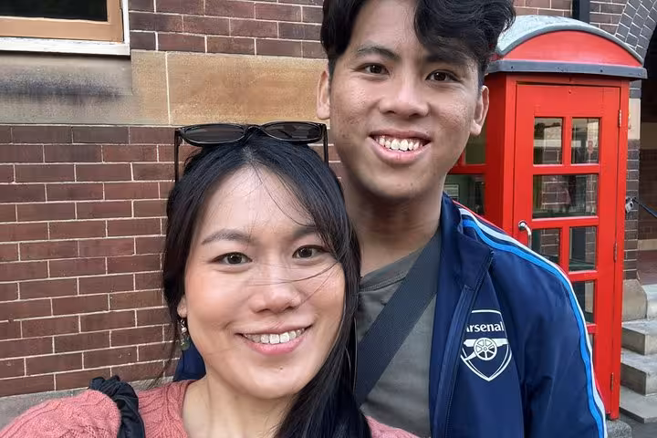 Two smiling tourists posing near a red British phone box on Sydney ghost walking tour