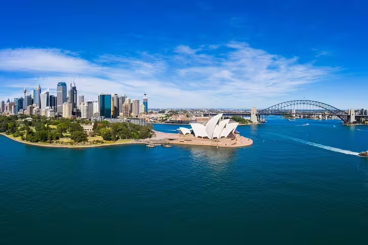 Aerial view of Sydney Harbour with Opera House, Harbour Bridge, and city skyline on a sunny day