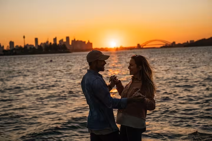 Couple enjoying a romantic sunset with Sydney skyline and Harbour Bridge view on a private tour.