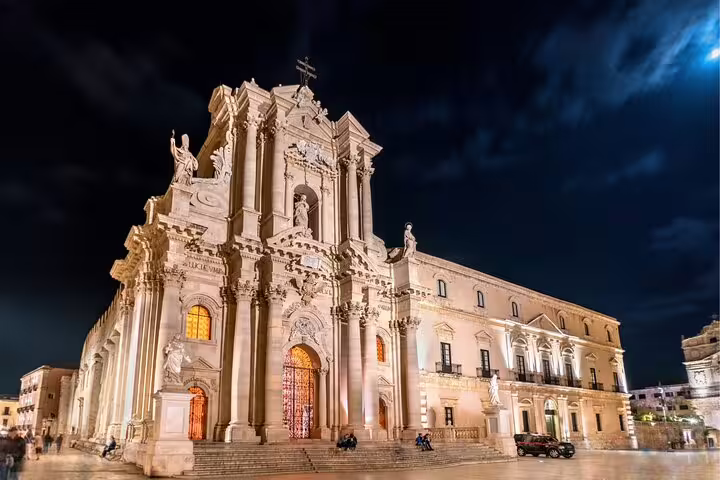 Illuminated Syracuse Ortigia Cathedral at night, key stop on a self-guided scavenger hunt highlights tour