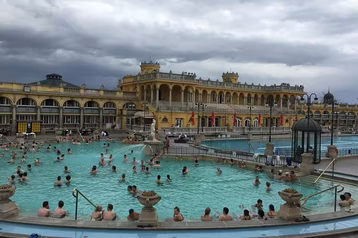 Tourists enjoy relaxing in the vibrant Széchenyi Thermal Bath in Budapest, a highlight on the private day trip from Vienna.