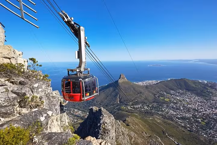 Cable car ascending Table Mountain with breathtaking views of Cape Town and the Atlantic Ocean in the background.