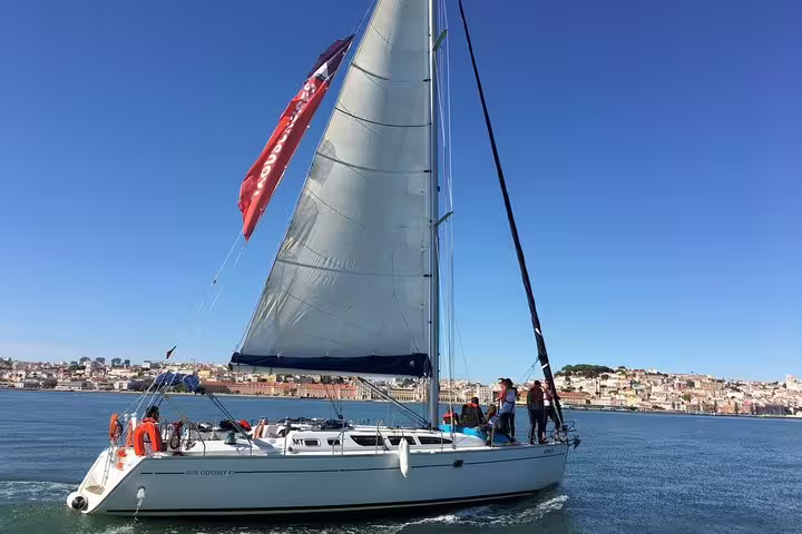 Tourists enjoying a sailing adventure on the Tagus River with Lisbon's skyline in view.