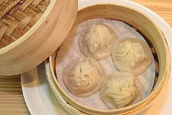 A bamboo steamer with four freshly made xiaolongbao dumplings at Taipei Hungzhou Xiaolongbao.