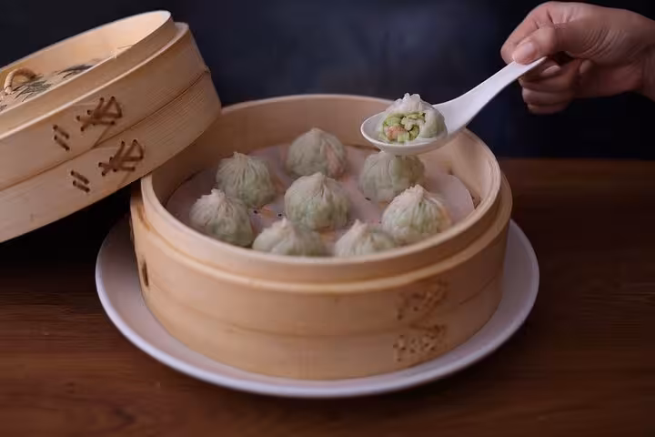 Delicious green Xiaolongbao dumplings served in a bamboo steamer at Taipei Hungzhou Xiaolongbao, showcasing authentic Taiwanese cuisine.