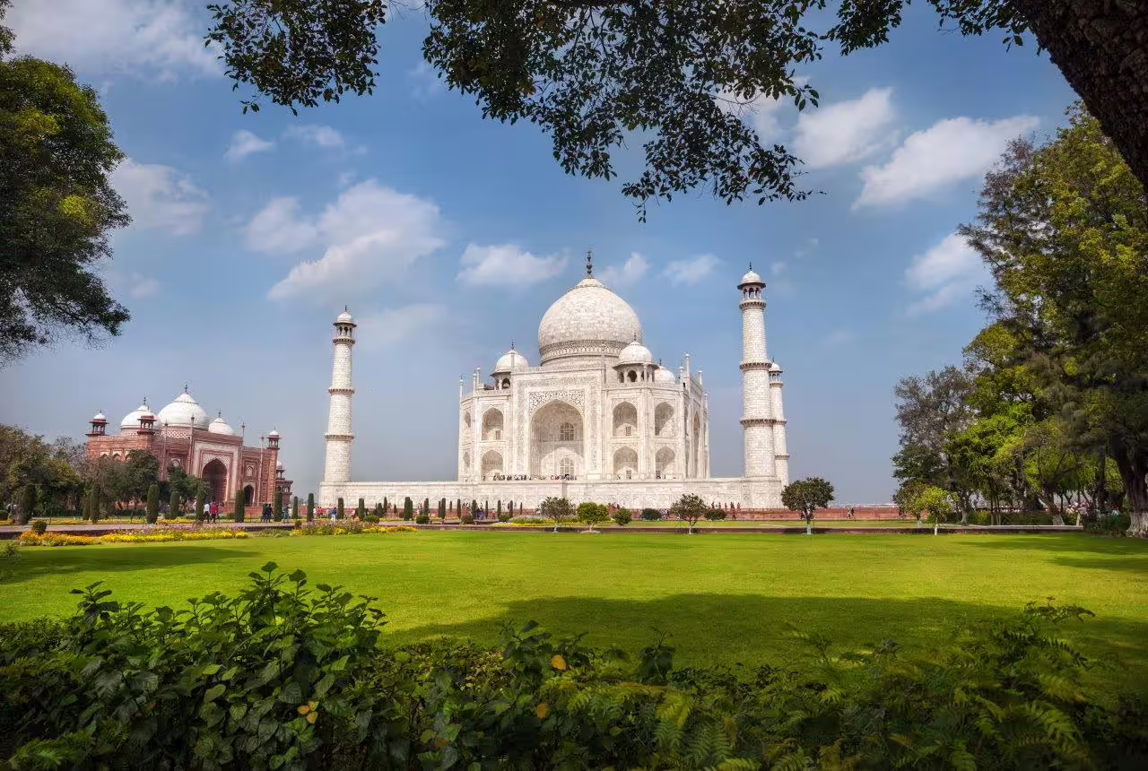 Majestic view of the Taj Mahal with lush gardens under a clear blue sky on the Golden Triangle tour.