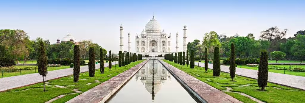 Explore the iconic Taj Mahal with its stunning reflection in a serene pool, perfect for the Classic Golden Triangle tour.