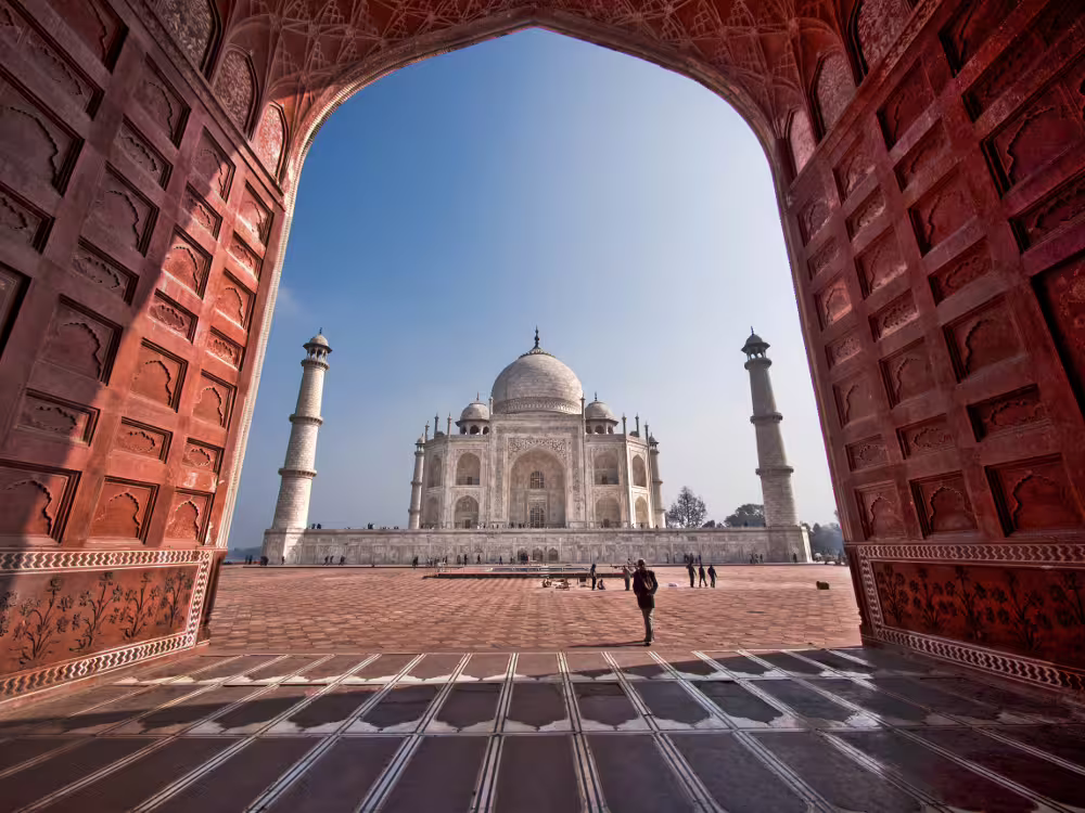 Majestic view of the Taj Mahal framed by red sandstone arch, featured in the Golden Triangle 6 days tour.