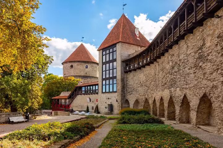 Medieval stone towers and defensive walls of Tallinn Old Town surrounded by autumn trees