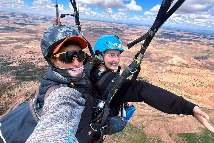 Smiling participants enjoy tandem paragliding over the Agafay Desert in Marrakech, capturing the thrill of this adventure.