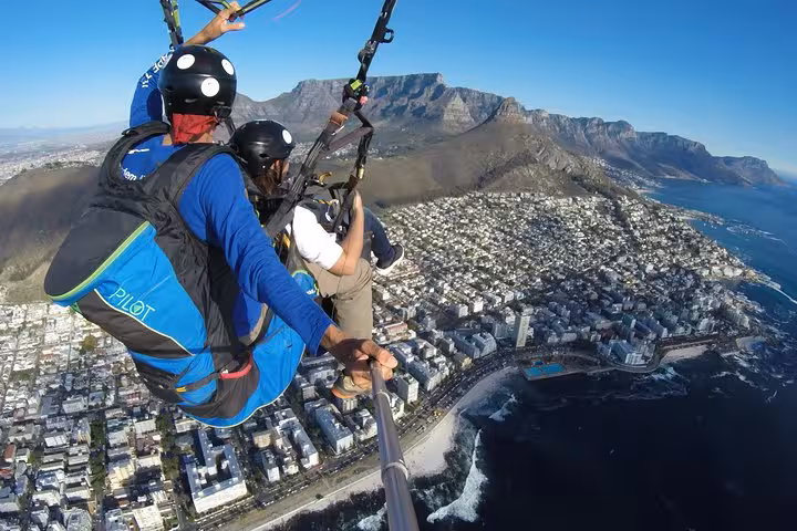 Aerial view of tandem paragliding above Cape Town's coastline and Table Mountain in clear skies.