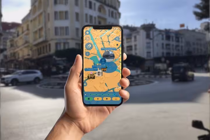 Hand holding smartphone displaying GPS walking tour map of Tangier International Zone with landmarks