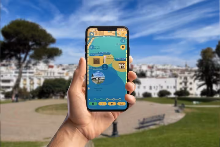 Hand holding smartphone displaying GPS walking tour map app of Tangier International Zone with landmarks