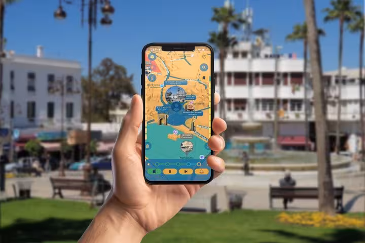 Hand holding smartphone displaying GPS walking tour map of Tangier International Zone with landmarks