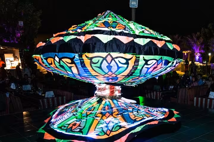 Colorful illuminated Tanoura dance costume spinning during a live show at Abu Dhabi desert safari BBQ dinner